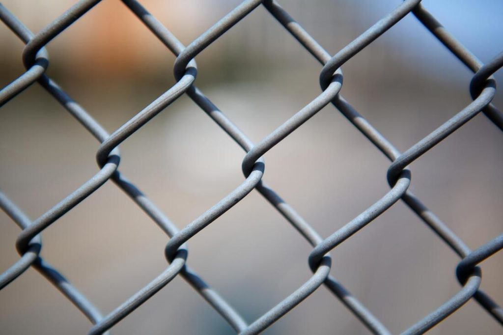 A close up picture of a chain link fence with a blurred backround