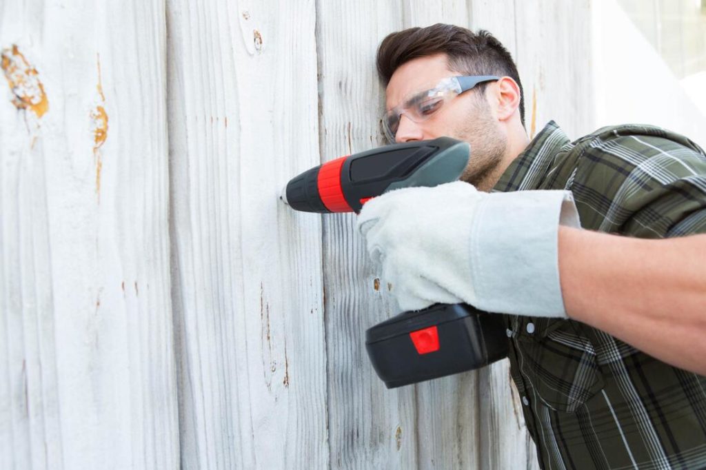 A picture of a guy drilling fence pieces together for a fence repair